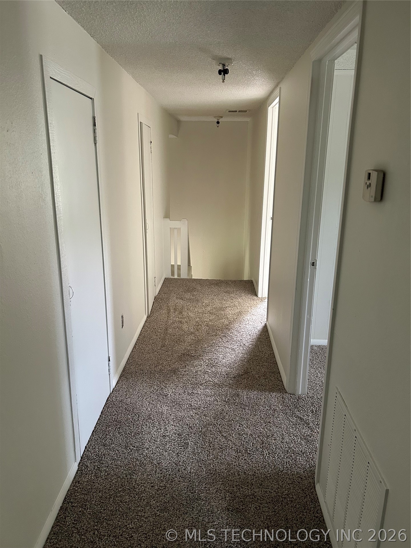 110955 East 1110 Road Sallisaw, OK 74955 - Photo 20 of 22 Carpeted hallway featuring multiple white paneled doors and a white painted banister