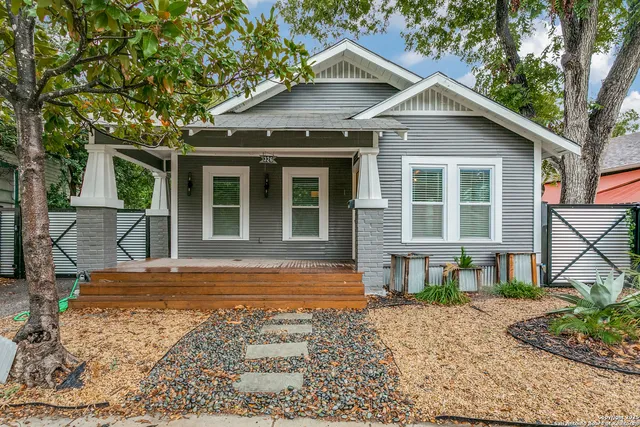 a view of a house with a yard and large tree