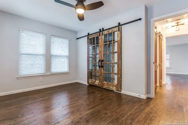 a view of an empty room with wooden floor and a window