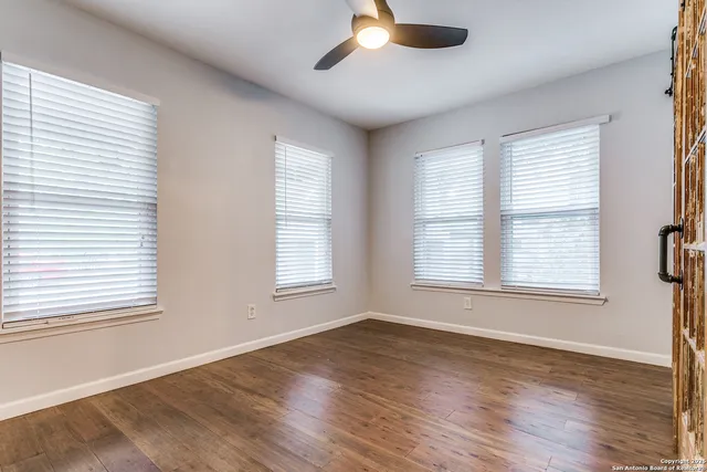 a view of an empty room with wooden floor and a window