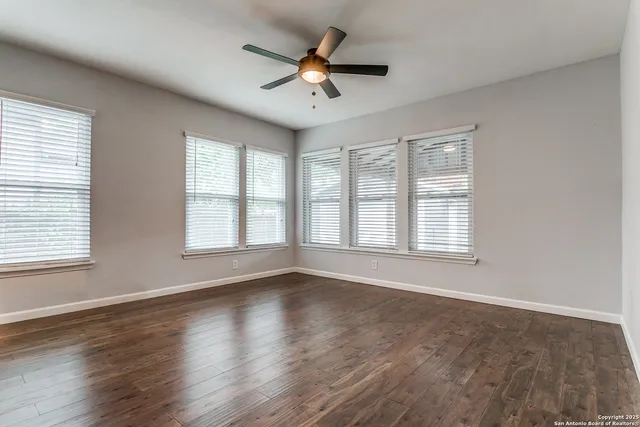 a view of an empty room with wooden floor and a window