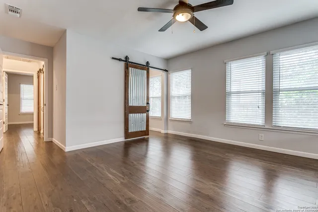 a view of an empty room with wooden floor and a window