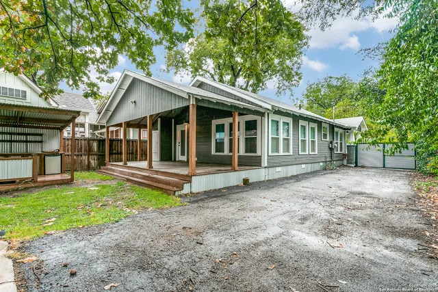 a view of a house with a yard and a large tree