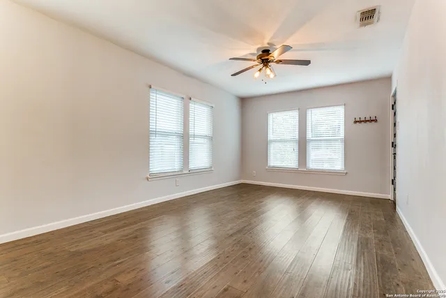 a view of an empty room with wooden floor and a window