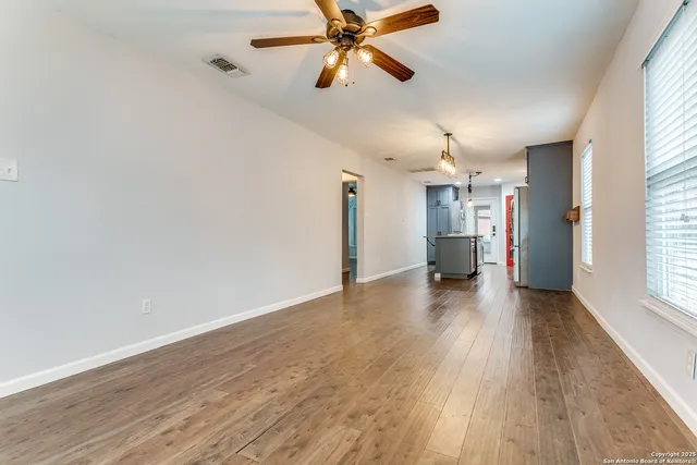 a view of empty room with wooden floor and fan