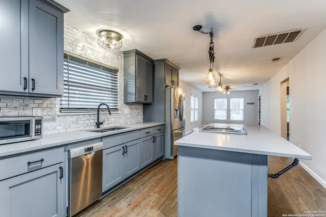 a kitchen with stainless steel appliances granite countertop a sink a stove and a wooden floors