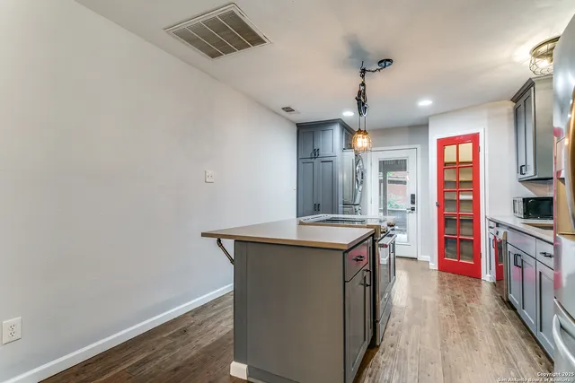 a kitchen with stainless steel appliances granite countertop a sink and a wooden floor