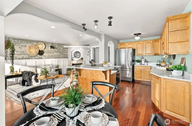 a very nice looking open dining room with kitchen island furniture a large window and a sink