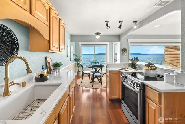 a kitchen with stainless steel appliances granite countertop a stove top oven a sink dishwasher and cabinets with wooden floor