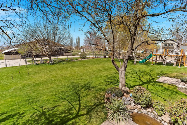 5321 South 3100th Street West Roy, UT 84067 - Photo 11 of 64 Expansive green lawn with mature trees and a built-in water feature