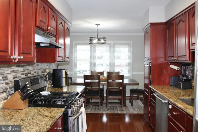 a kitchen with stainless steel appliances granite countertop a stove top oven a sink dishwasher and cabinets with wooden floor