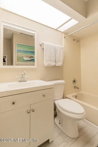 a bathroom with a toilet sink vanity shower and mirror
