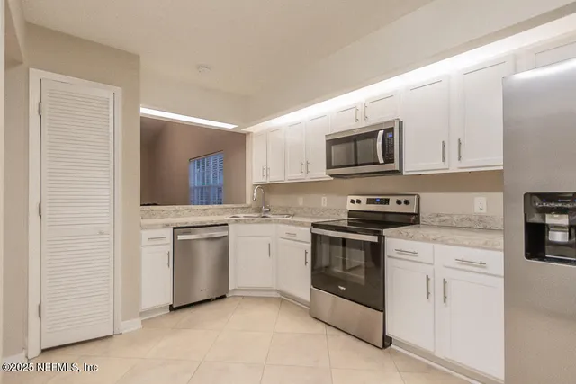 a kitchen with white cabinets stainless steel appliances and sink