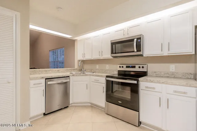 a kitchen with white cabinets appliances and sink