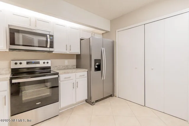a kitchen with stainless steel appliances white cabinets and a refrigerator