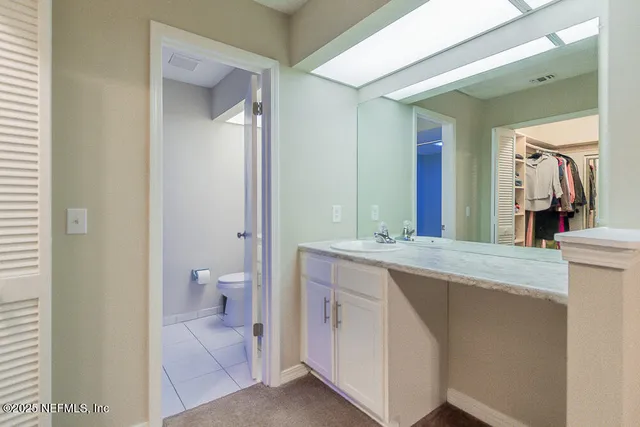 a spacious bathroom with a granite countertop sink a toilet and a mirror