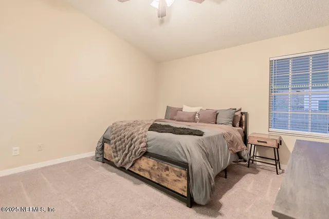 a bed sitting in a bedroom next to a window with lamp