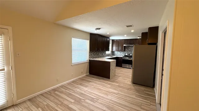 an empty room with wooden floor cabinet and windows