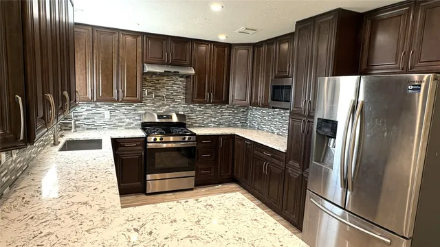 a kitchen with kitchen island stainless steel appliances a sink stove and refrigerator