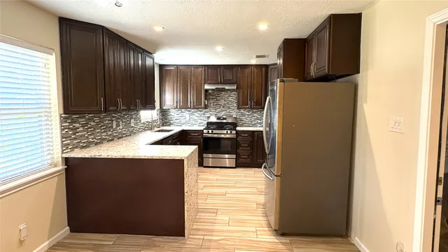 a kitchen with granite countertop stainless steel appliances and refrigerator