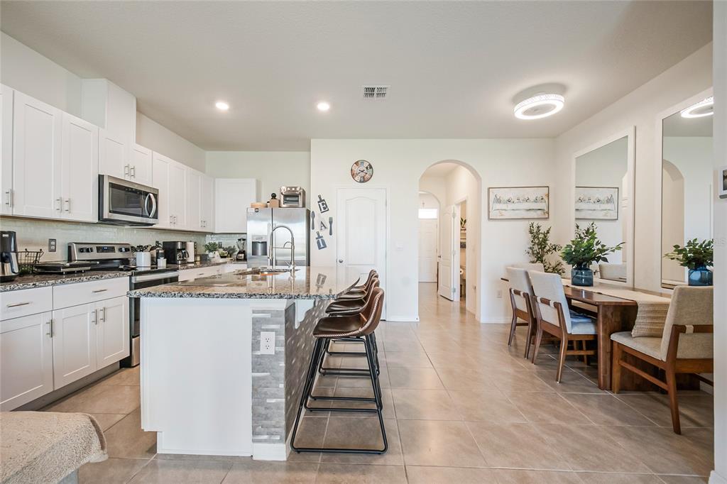 1359 Isleta Loop Kissimmee, FL 34741 - Photo 13 of 57 a kitchen with stainless steel appliances granite countertop a table and chairs in it