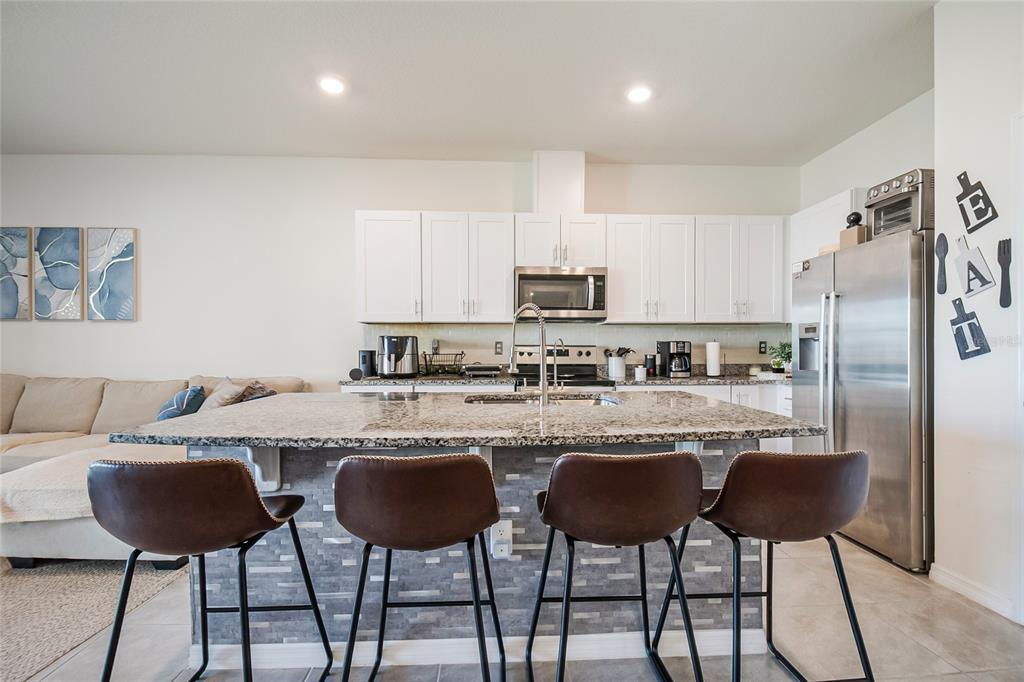 1359 Isleta Loop Kissimmee, FL 34741 - Photo 14 of 57 a kitchen with stainless steel appliances a dining table chairs microwave and sink