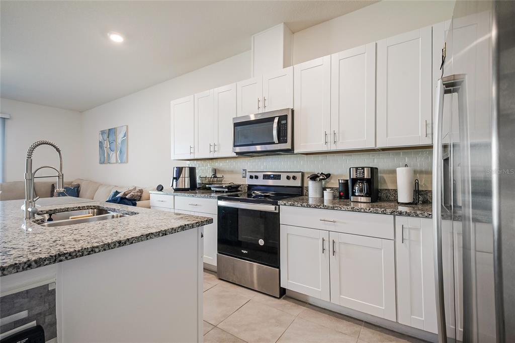 1359 Isleta Loop Kissimmee, FL 34741 - Photo 15 of 57 a kitchen with granite countertop a sink stainless steel appliances and white cabinets