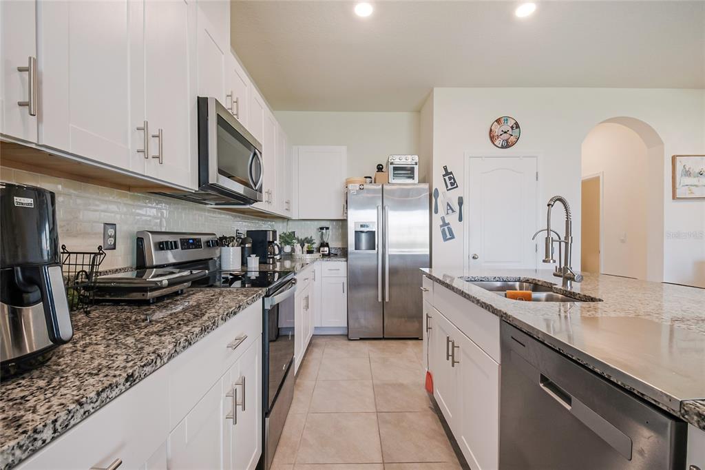 1359 Isleta Loop Kissimmee, FL 34741 - Photo 18 of 57 a kitchen with stainless steel appliances granite countertop a sink stove and refrigerator