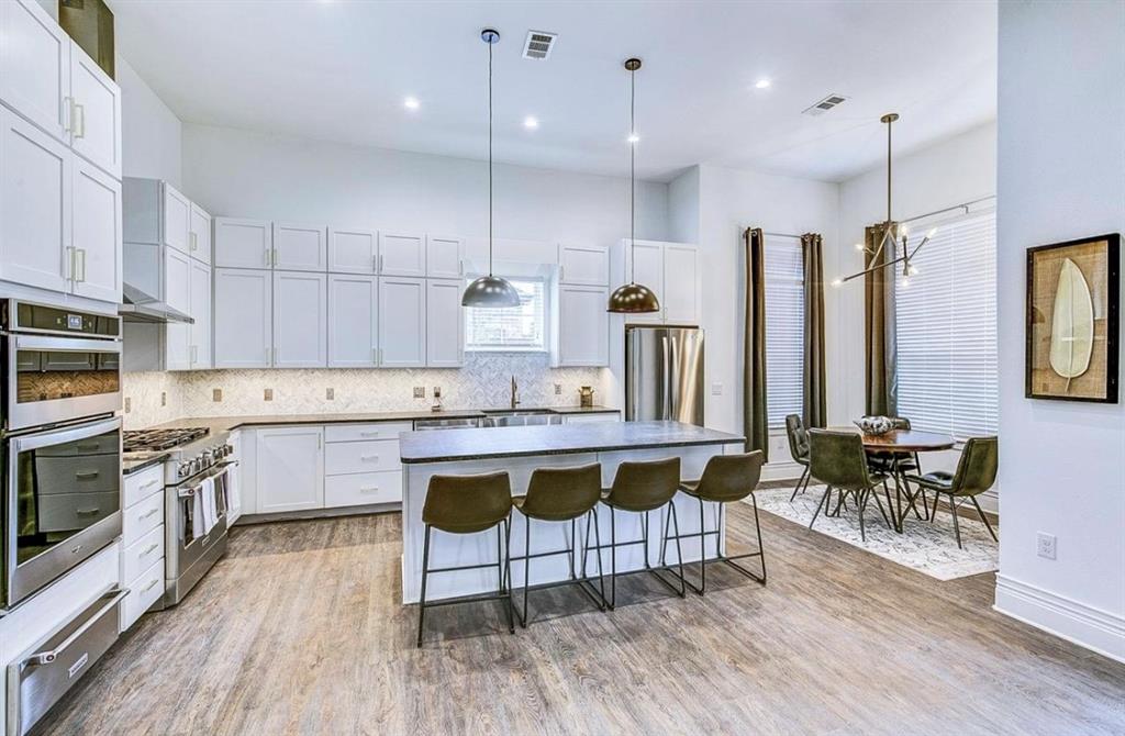12001 Inwood Road, Unit 3501 Dallas, TX 75244 - Photo 6 of 15 Kitchen featuring appliances with stainless steel finishes, a center island, tasteful backsplash, a breakfast bar area, and hanging light fixtures