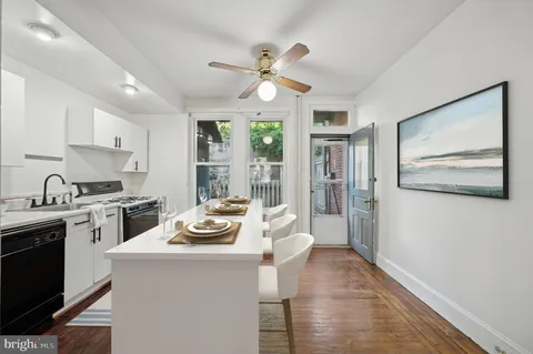 a kitchen with stainless steel appliances a stove a sink dishwasher a refrigerator and white cabinets with wooden floor