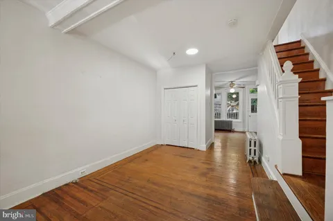 a view of an empty room with wooden floor and stairs