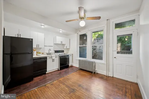 a kitchen with stainless steel appliances granite countertop a refrigerator a sink a stove and white cabinets with wooden floor