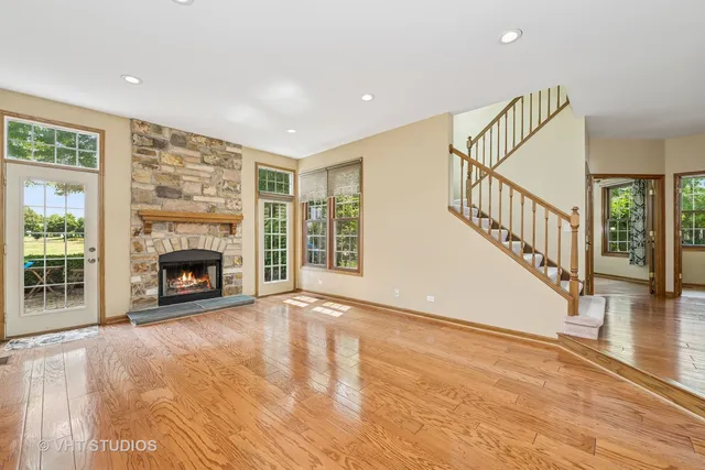 a view of an empty room with wooden floor fireplace and a window
