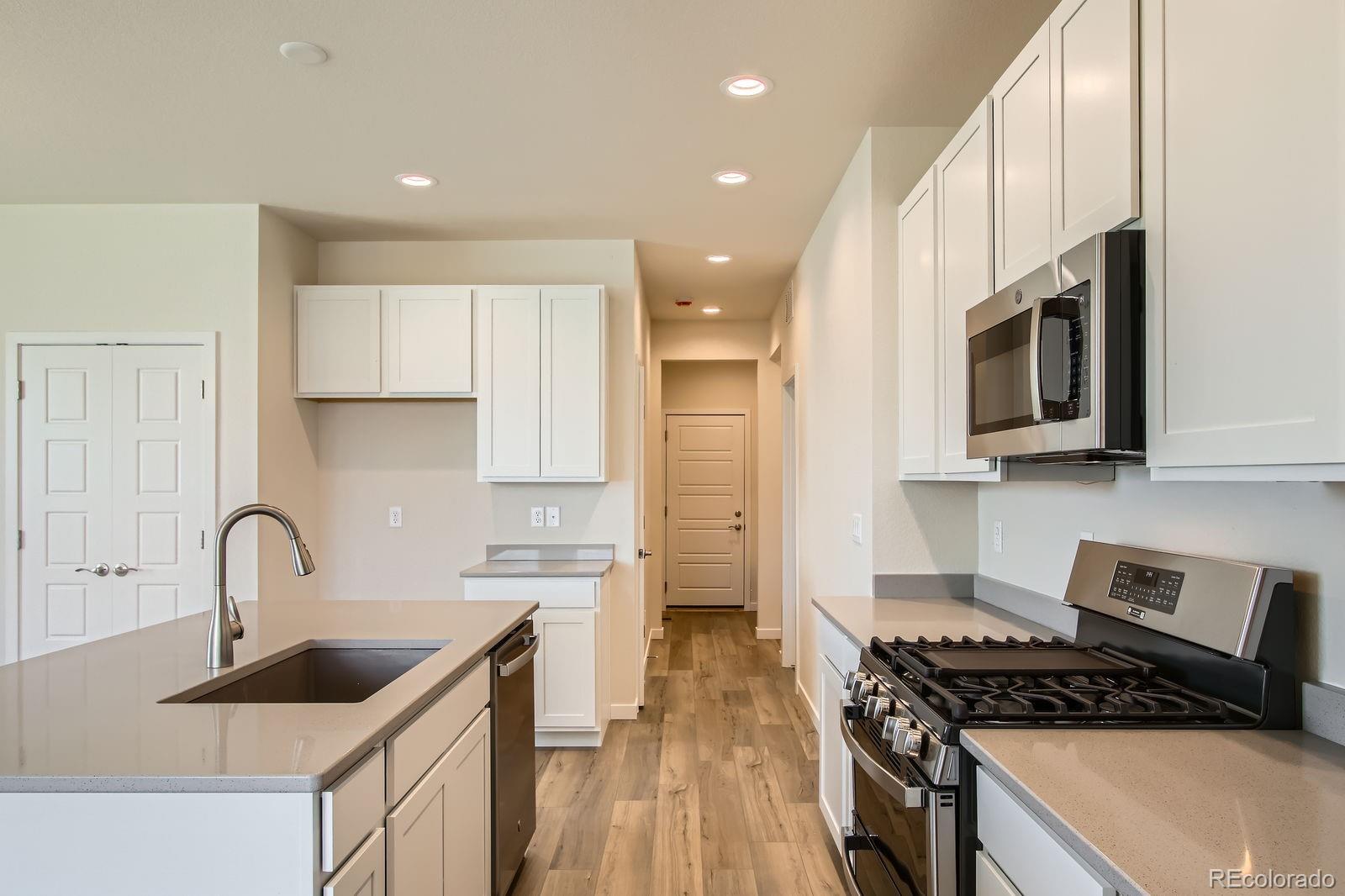 9085 Rifle Street Commerce City, CO 80022 - Photo 12 of 31 a kitchen with stainless steel appliances a sink a stove top oven a counter space and cabinets