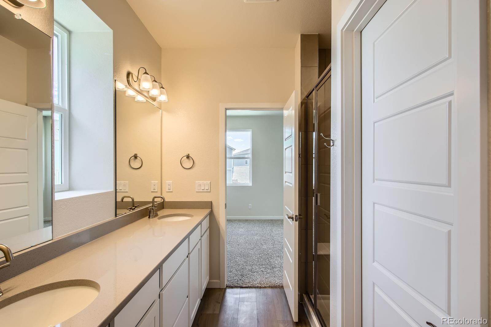 9085 Rifle Street Commerce City, CO 80022 - Photo 18 of 31 a spacious bathroom with a granite countertop sink mirror and a shower