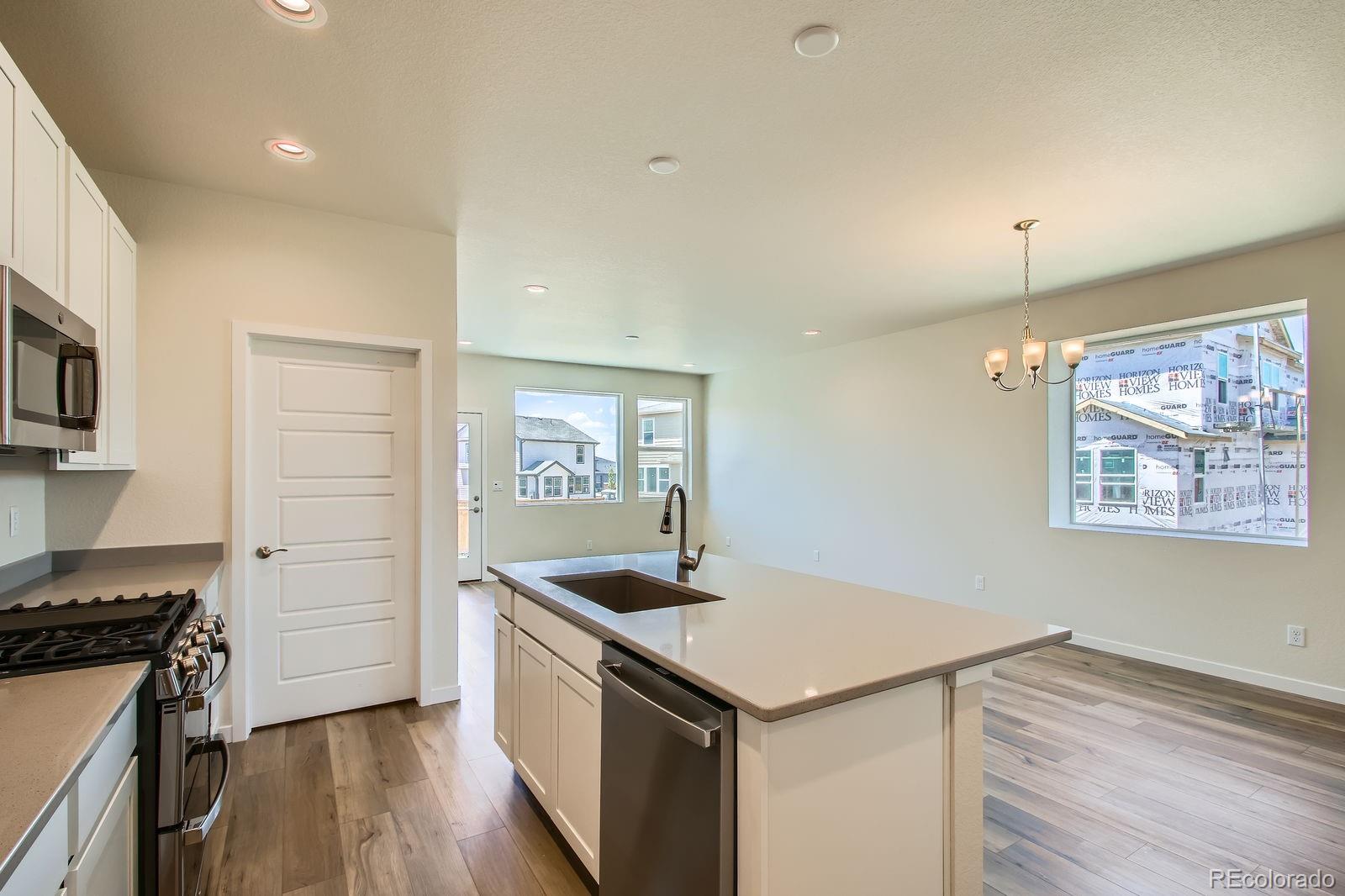 9085 Rifle Street Commerce City, CO 80022 - Photo 9 of 31 a kitchen that has a sink a stove and wooden floor