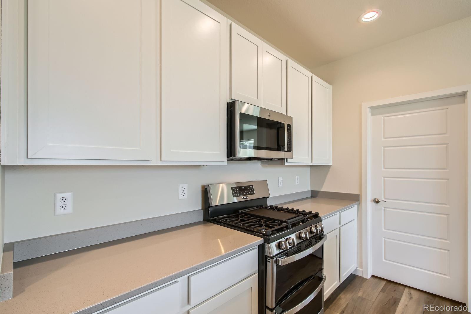 9085 Rifle Street Commerce City, CO 80022 - Photo 10 of 31 a kitchen with stainless steel appliances granite countertop white cabinets and a stove top oven