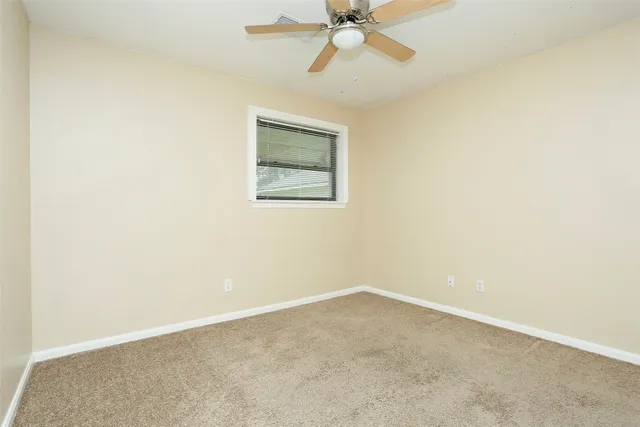 an empty room with a ceiling fan and a window