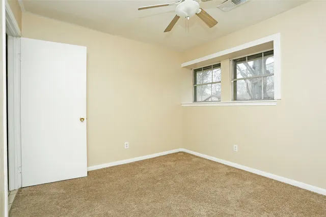 an empty room with fan and windows