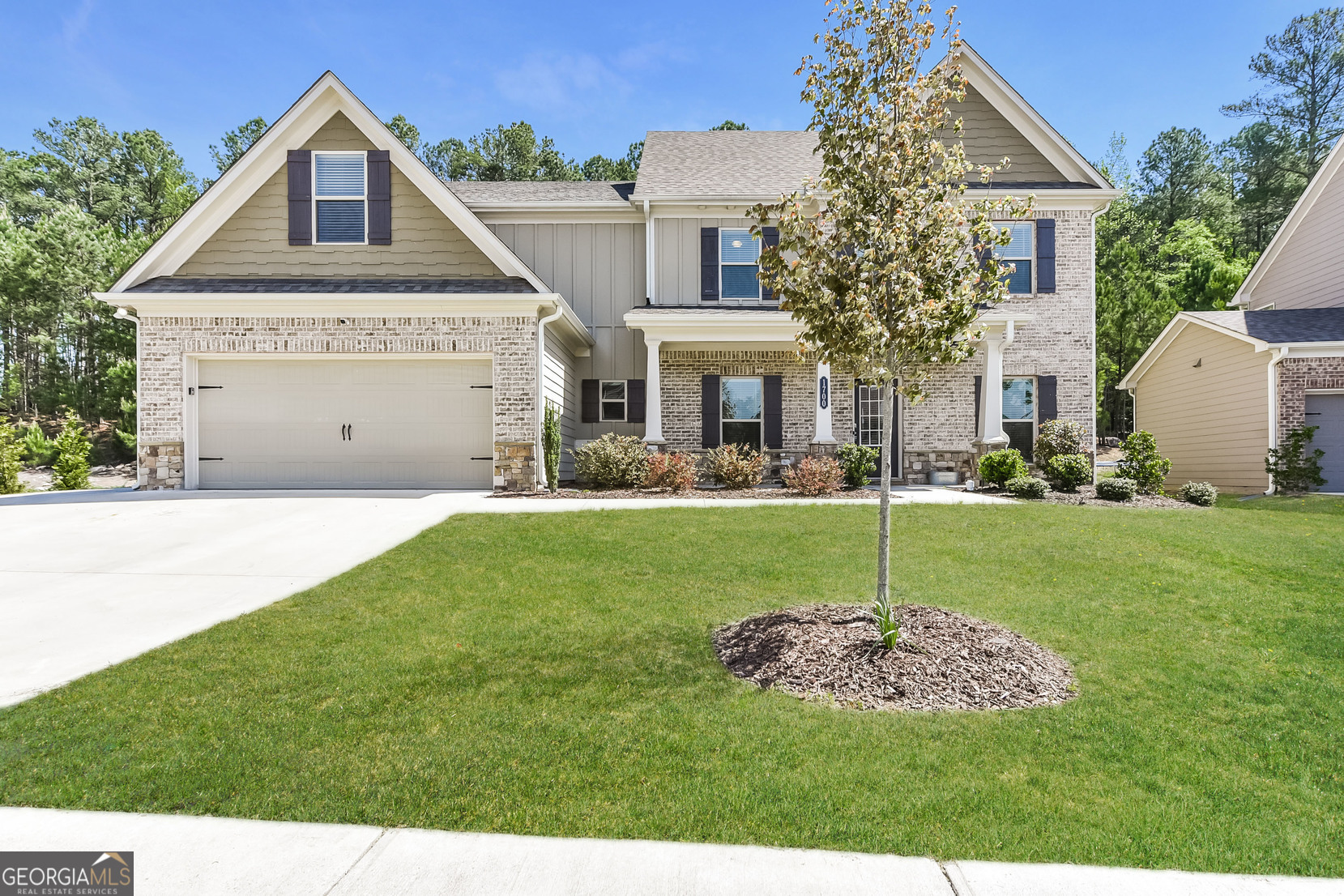 a view of a house with a big yard potted plants and large tree