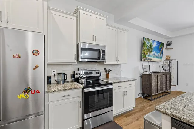 a kitchen with stainless steel appliances white cabinets and a stove top oven