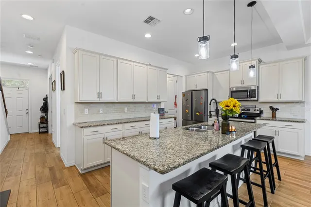a kitchen with stainless steel appliances granite countertop a stove top oven a refrigerator a sink and white cabinets