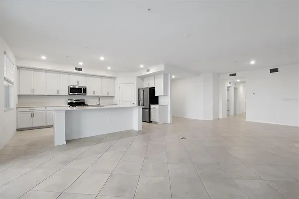 a large white kitchen with kitchen island a sink a stove a refrigerator and white cabinets