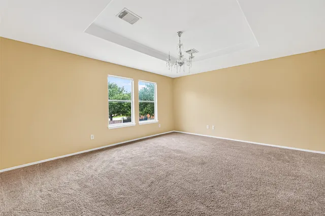 an empty room with windows and chandelier fan