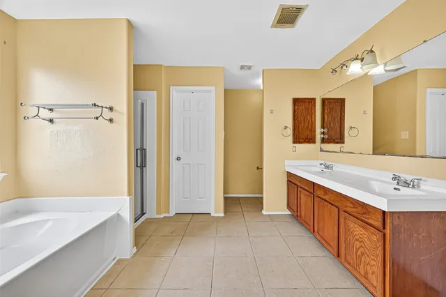 a spacious bathroom with a tub sink shower and mirror