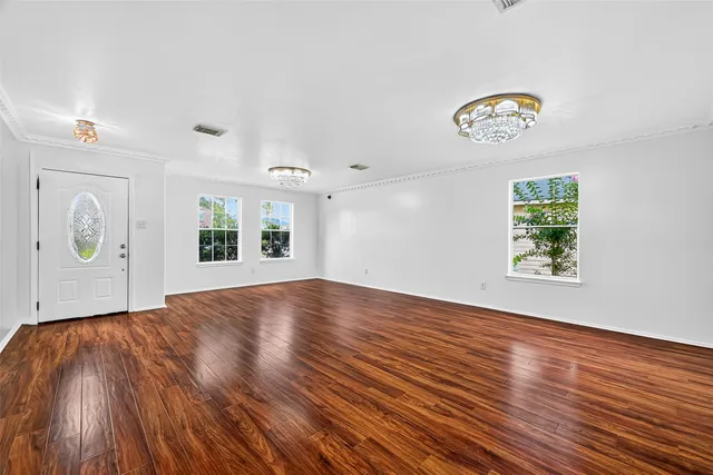an empty room with wooden floor and window