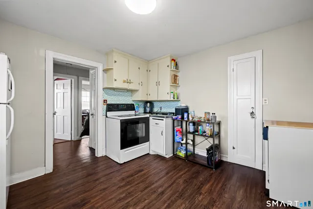 a kitchen with granite countertop white cabinets and wooden floor