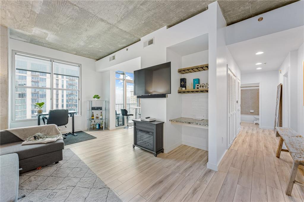 a large living room with stainless steel appliances furniture a flat screen tv and a large window