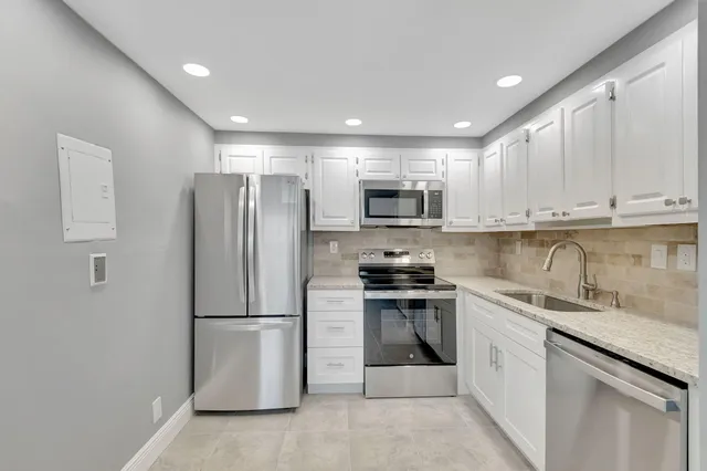a kitchen with stainless steel appliances granite countertop a refrigerator sink and stove