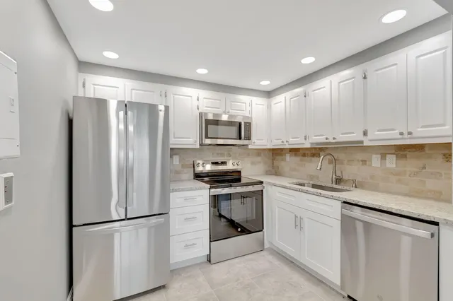 a kitchen with stainless steel appliances granite countertop a refrigerator sink stove microwave and cabinets